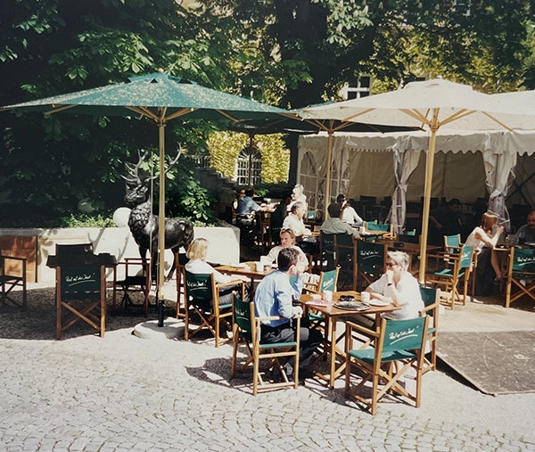 Historisches Foto eines Biergartens mit Regiestühlen in Braun und grünem Branding – ein früher Einsatz von Pedro-Stühlen in der Gastronomie.