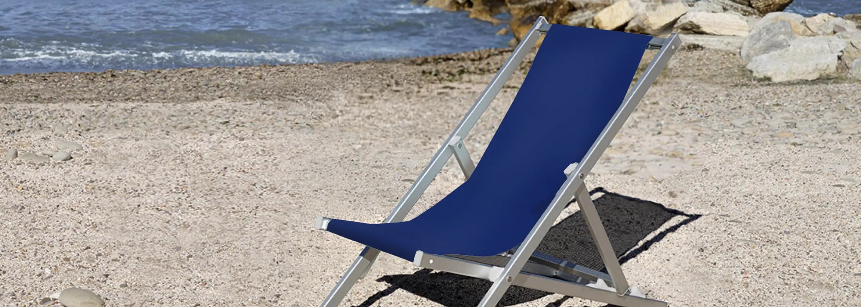 Blauer Liegestuhl Quentin aus Aluminium am Strand mit Blick auf das Meer.