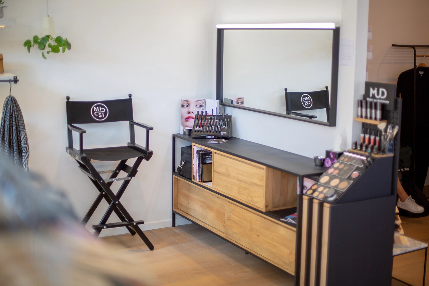 Schwarzer, hoher Regiestuhl Steven mit Logo-Druck in einem modernen Make-up-Studio mit Holzkommode, Spiegel und professionellem Schminksortiment. Stilvolle Ausstattung für Kosmetik- und Stylingbereiche.