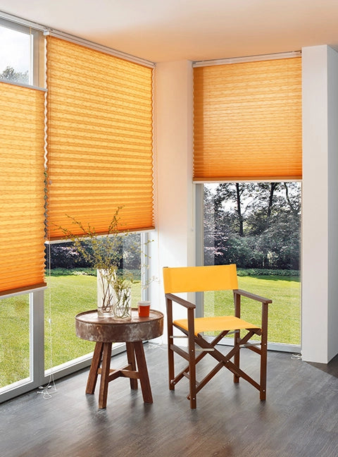 Regiestuhl Woody in braun mit gelbem Bezug im Wohnzimmer vor bodentiefen Fenstern mit Plissees.