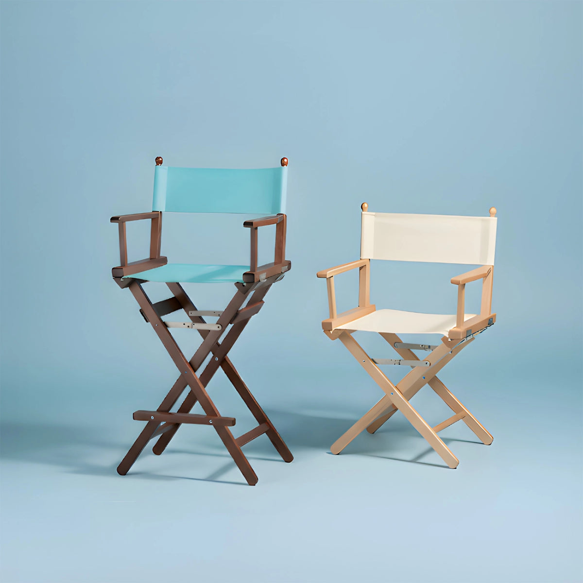 Zwei Regiestühle mit unterschiedlich farbigen Stoffen und Holzgestellen vor hellblauem Hintergrund (quadratisch)