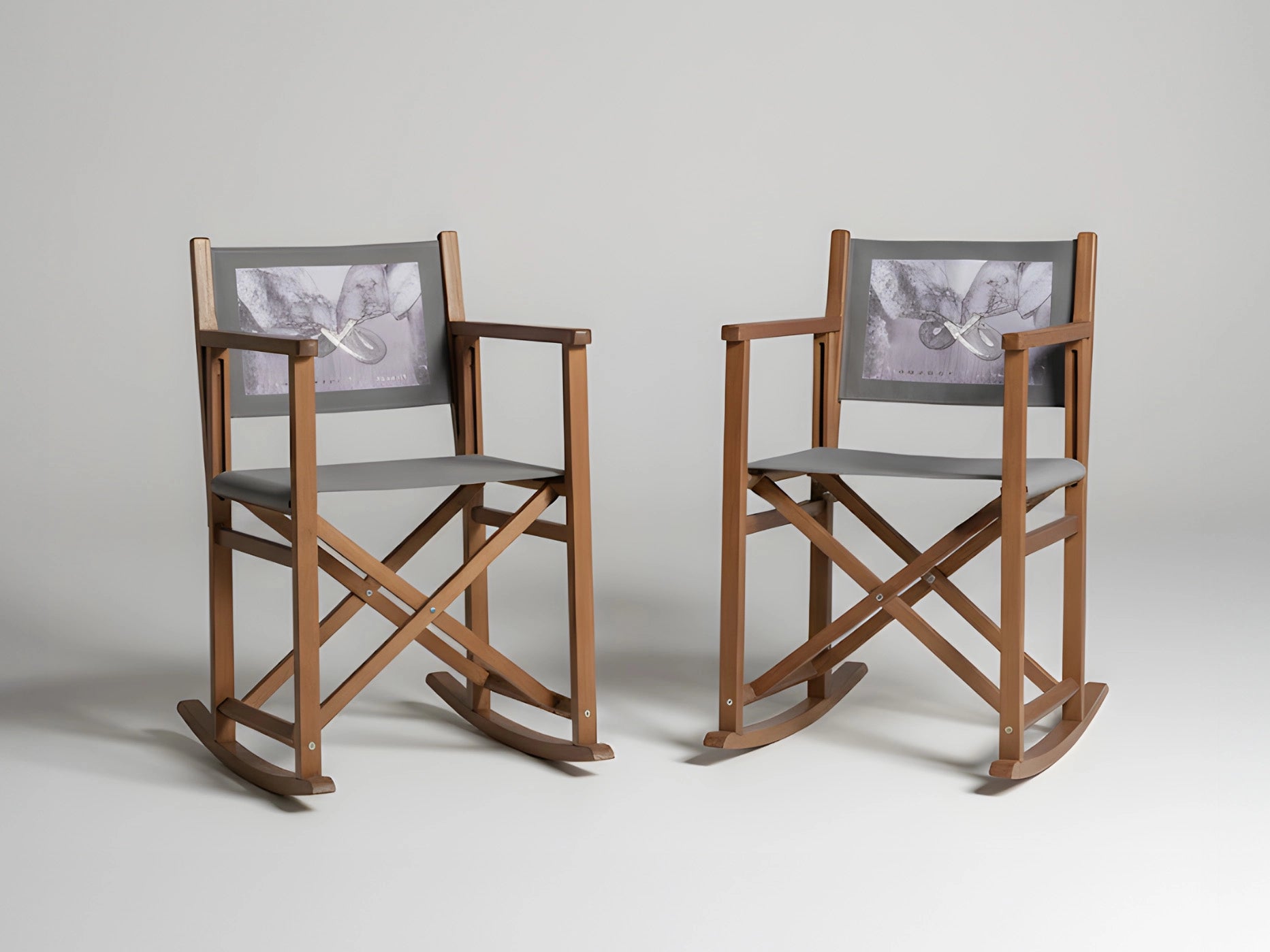 Zwei Schaukel-Regiestühle mit grauen Stoffen und individuellem Druck vor neutralem Hintergrund