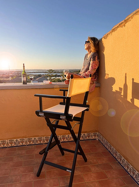 Hoher Regiestuhl Steven in schwarz lackiertem Holz und weißem Stoff steht bei Sonnenuntergang auf einer Terrasse.