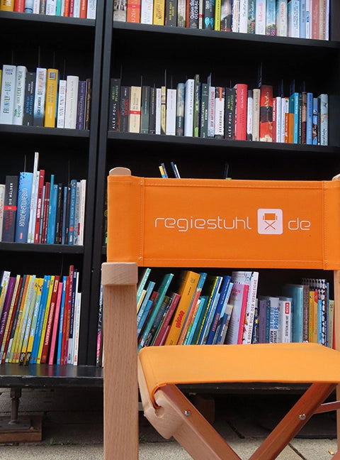 Eine Nahaufnahme eines Kinderstuhls Nanni mit naturfarbenem Gestell und Bezug in mandarine inklusive Logo-Druck für den Einsatz in einer Bibliothek.