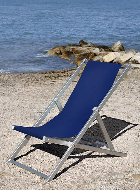 Liegestuhl Quentin in silbernem Aluminium und mit dunkelblauen Stoff steht an einem Strand am Meer.