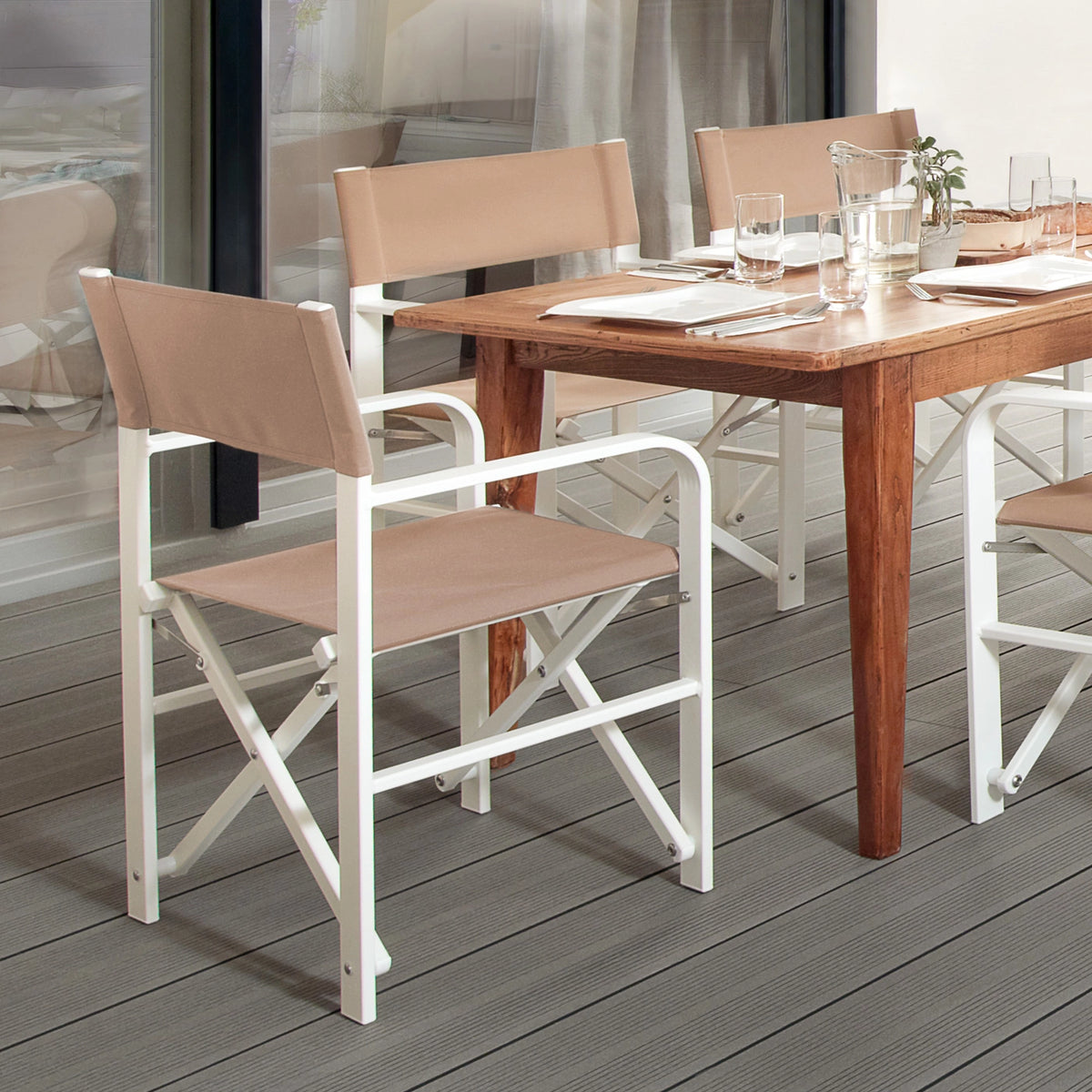 Regiestühle Sofia mit weißem Aluminiumgestell und grau-beigem Stoff um einen Esstisch auf einer modernen Gartenterrasse – stilvolle Sitzlösung für Balkon, Garten oder Outdoor-Essbereiche.