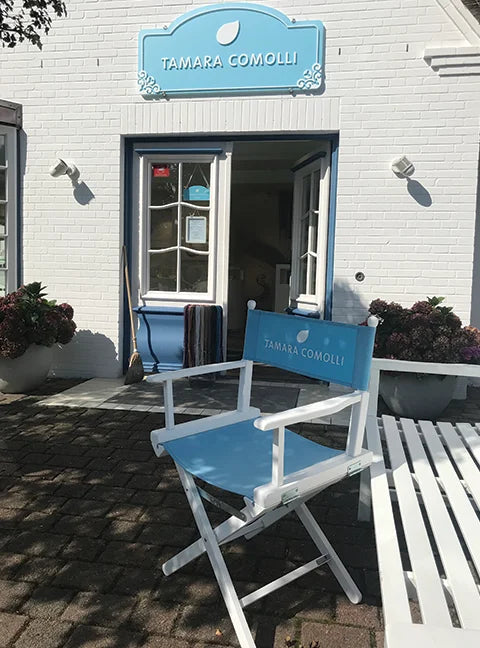Regiestuhl mit Tamara Comolli Logo vor einem stilvollen Ladengeschäft – Beispiel für individuelles Corporate Branding mit Firmenlogo.