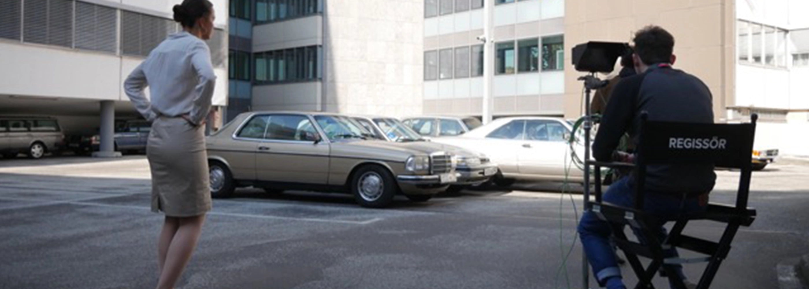 Regisseur bei Dreharbeiten in einem Innenhof, sitzt auf einem Regiestuhl Steven mit Druck „REGISSÖR".