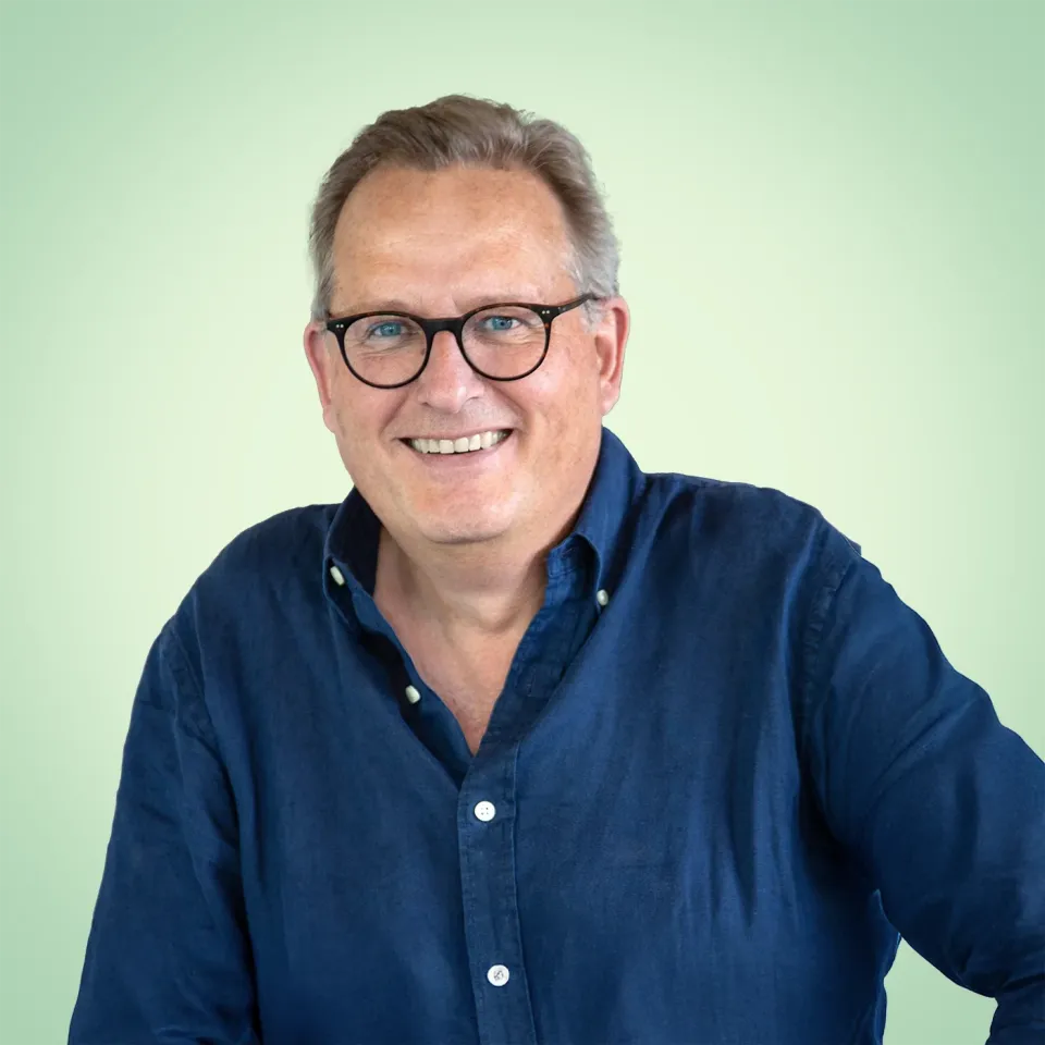 Lars vom Regiestuhl-Team mit Brille und offenem Hemd vor hellgrünem Hintergrund