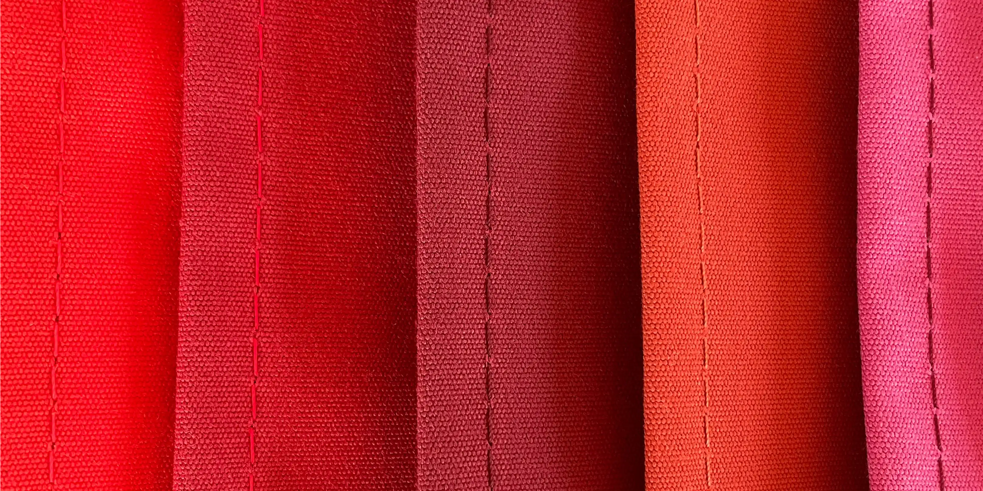 Nahaufnahme roter Stoffmuster mit Nähten – Teaserbild für den Stofffinder auf Regiestuhl.de.