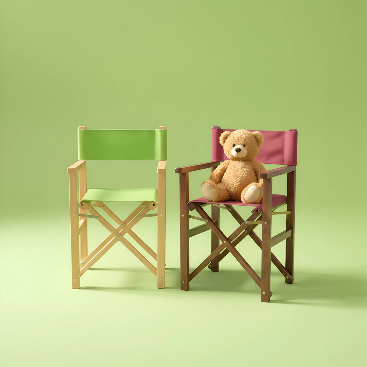 Zwei farbige Kinder-Regiestühle, einer mit Teddybär, vor grünem Hintergrund (quadratisch)
