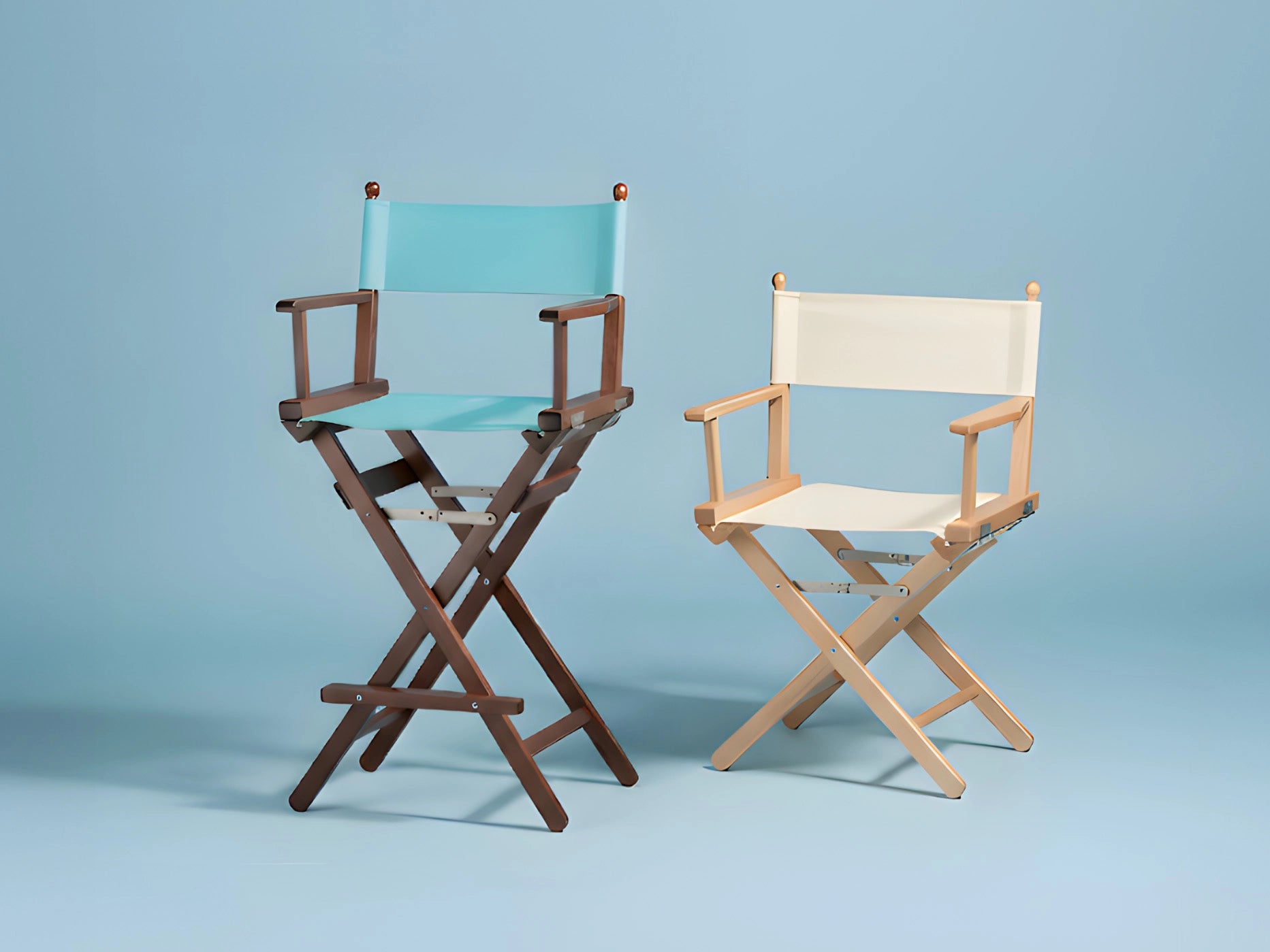 Zwei Regiestühle mit unterschiedlich farbigen Stoffen und Holzgestellen vor hellblauem Hintergrund