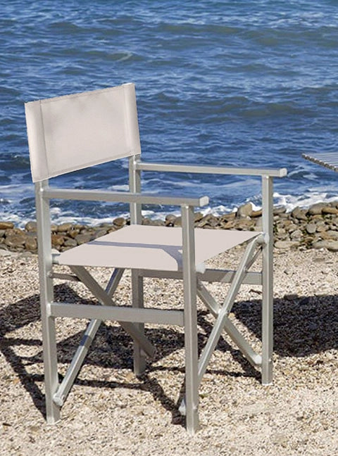 Wetterfester Outdoor-Regiestuhl Stanley mit silbernem Aluminiumgestell und hellgrauem Bezug steht am Strand am Meer.